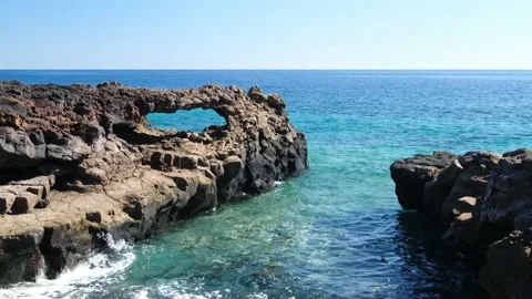 Volcanic basalt coast with a rock arch surrounded by blue Ocean on El Hierro Stock Footage 179600964