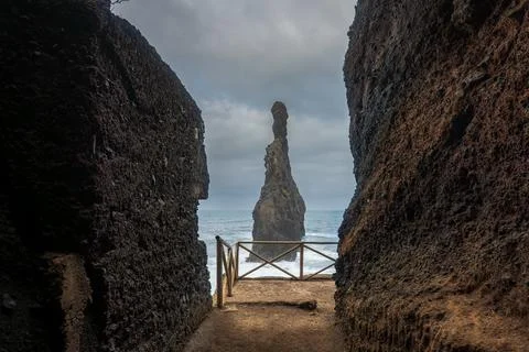 Volcanic cliffs frame sea stack and wooden lookout in Madeira Foto stock