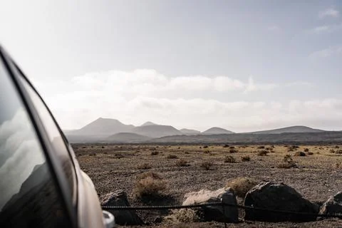 Volcanic landscape with distant mountains and a vehicle in front Stock Photos