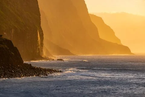 Volcanic rock cliffs Achadas da Cruz in sunlight. Sunset seascape of Madeira Stock Photos