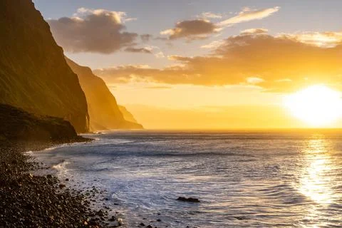 Volcanic rock cliffs Achadas da Cruz in sunlight. Sunset seascape of Madeira Stock Photos