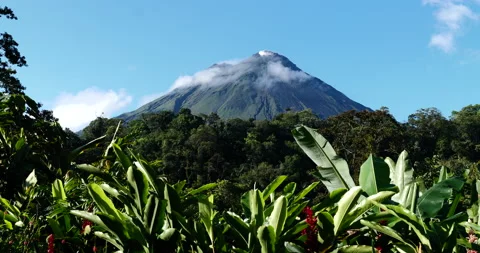 Volcano with clouds moving at the peak and green plants in the foreground. Stock Footage 154711085