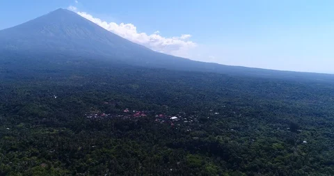 Volcano with its side covered in tropical vegetation, village at the bottom Video stock 114576372
