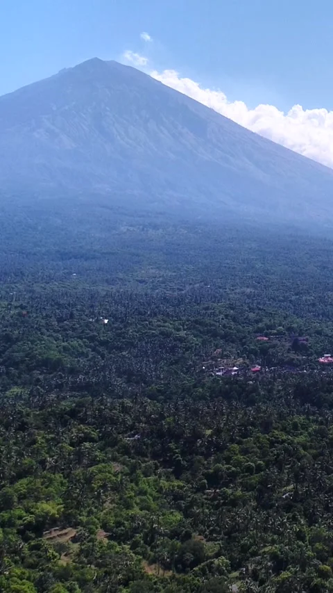 Volcano with its side covered in tropical vegetation, village at the bottom Stock Footage 228009920