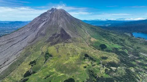 The volcano rises like a rugged stone pyramid above a patchwork of green meadows Fotos de archivo