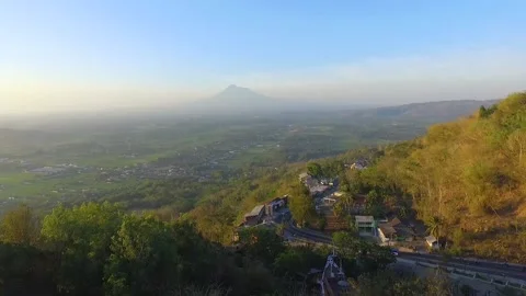 Volcanoes in Indonesia visible from a distance with traffic and country road Stock Footage