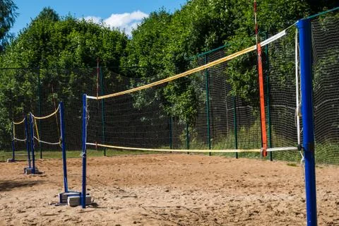 Volleyball net on blue poles on empty sand beach Stock Photos