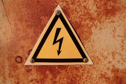 Voltage sign attached to a rusty background Stock Photos