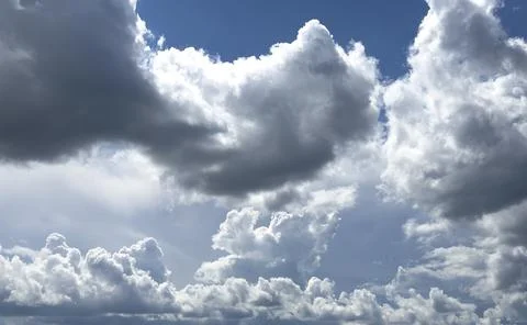 Voluminous clouds cluster across sky forming textured pattern. Bright light a Stock Photos