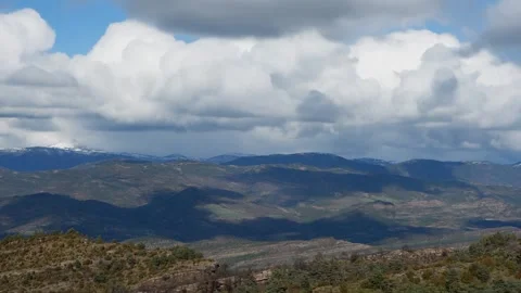 Voluminous clouds move over Pyrenees mountain range on a sunny spring day Stock Footage 329761757