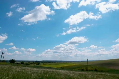 Voluminous white clouds in the blue sky, beautiful summer landscape, fields Stock Photos