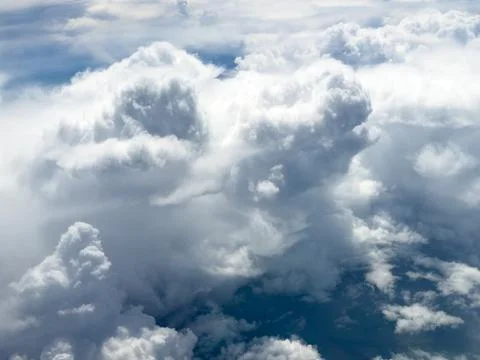Voluminous white clouds drift above deep blue sky Stock Photos