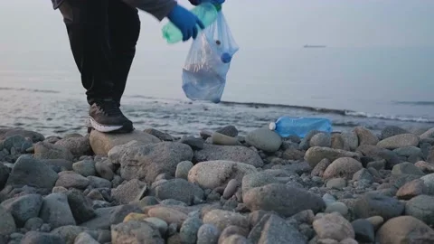 Volunteer cleaning beach from plastic garbage. Man picks up plastic bottles Stock Footage 226142348