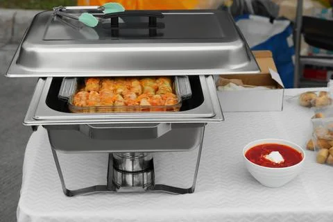 Volunteer food distribution. Metal warmer with tasty stuffed cabbage and bo.. Stock Photos