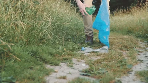 A volunteer guy picking up plastic garbage off green areas Stock Footage 157028057