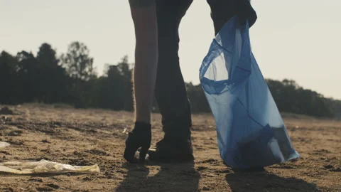 A volunteer guy picking up plastic garbage off sandy beach Stock Footage 157167146