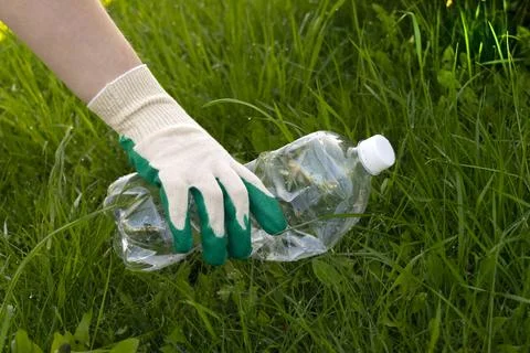 Volunteer hand pick empty plastic bottle are lying on the grass Stock Photos