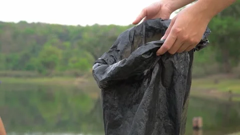 The volunteer picking up a bottle plastic in to the bin bag Видео 158532428