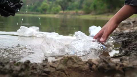 The volunteer picking up a bottle plastic in the river , protect environment Видео 158532452