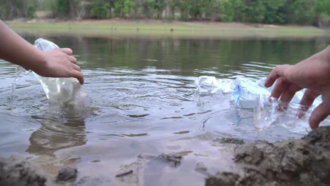 The volunteer picking up a bottle plastic in the river , protect environment Видео 158532480