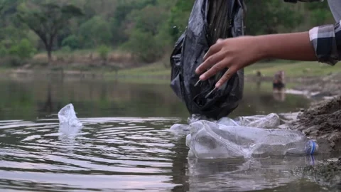 The volunteer picking up a bottle plastic in the river , protect environment Видео 158532505