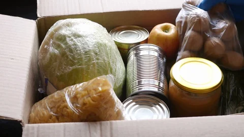 Volunteer puts food in a donation box, closeup. Charity and donations. Help Stock Footage