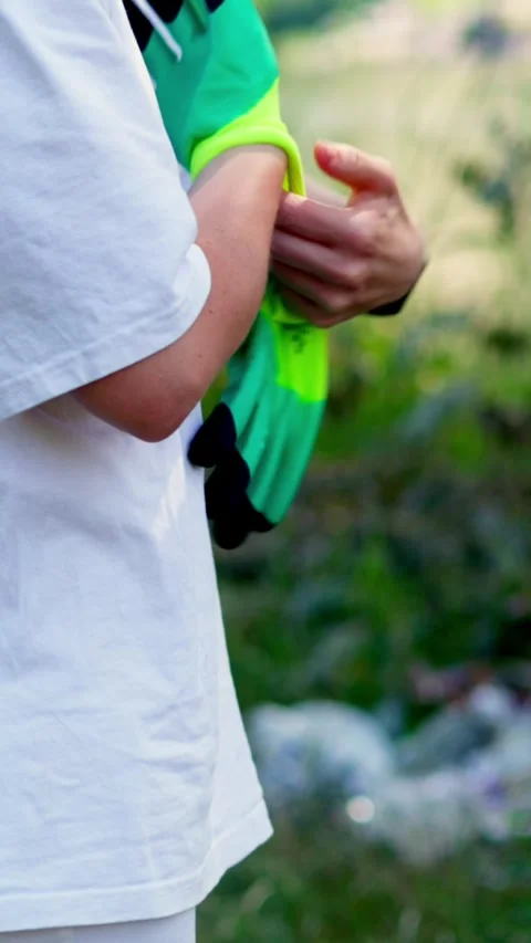 Volunteer puts on gloves to clean up trash on the riverbank Stock Footage 340577834