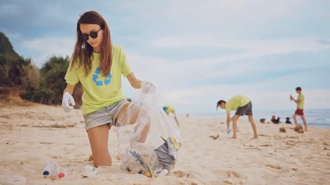 The volunteer raises and throws plastic garbage into the bag. Stock Footage 103274297
