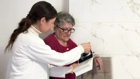 Volunteer shares her knowledge with an elderly woman while explaining Stock Footage 262692266