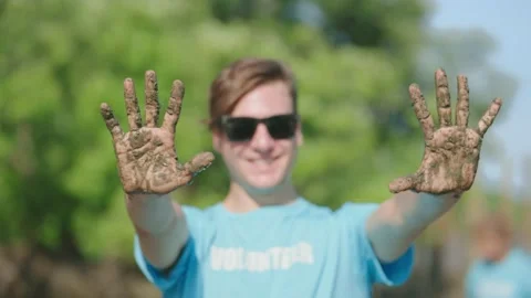 Volunteer showing hands soiled in mud sign smiling look at camera helpers plant Stock Footage 204834831