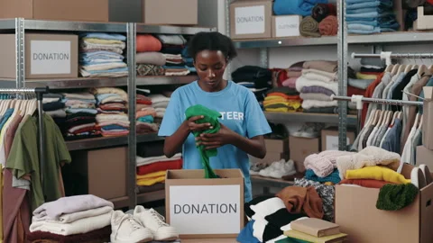Volunteer sorting out donated clothes in community charity donation center Stock Footage 197511916