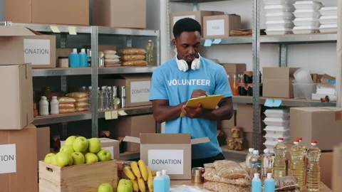 Volunteer using clipboard while packing donation boxes Stock Footage 190442331