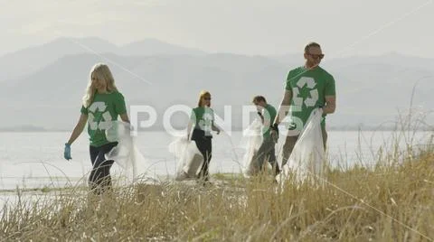 Volunteers collecting recycling and trash garbage on remote grassy lake shore Stock Photos