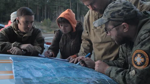 Volunteers explore the terrain and search boundaries on the hood of the car Stock Footage 166664582