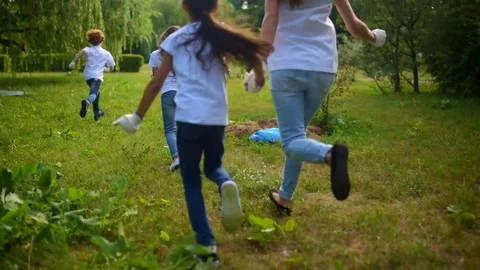 Volunteers playing catch up with children in park Stock Footage