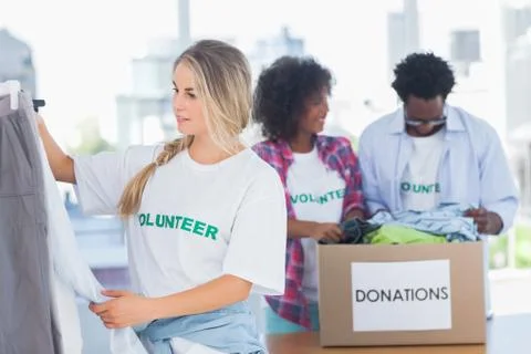 Volunteers putting clothes in clothes rail Stock Photos