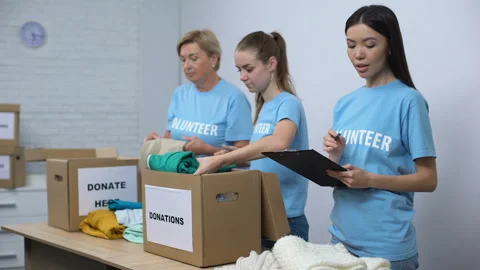 Volunteers putting clothes in donation boxes, smiling social worker making notes Stock Footage 113354270