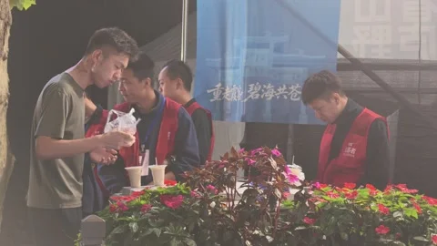 Volunteers in Red Vests Preparing Drinks at Refreshment Table, Lushan Stock Footage 346701382