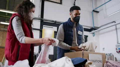 Volunteers sorting out donated clothes in community charity donation center Stock Footage 154644070