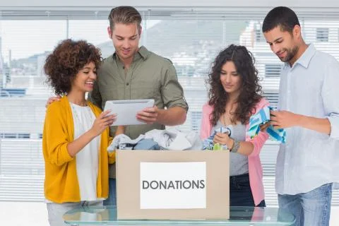 Volunteers using tablet and taking out clothes from a donation box Foto stock