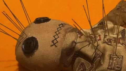Voodoo doll made of fabric with needles stuck in it Stock Footage 341579091