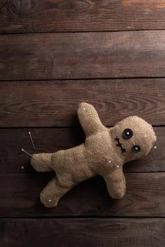 Voodoo doll on a wooden background with dramatic lighting. The concept of wit Stock Photos