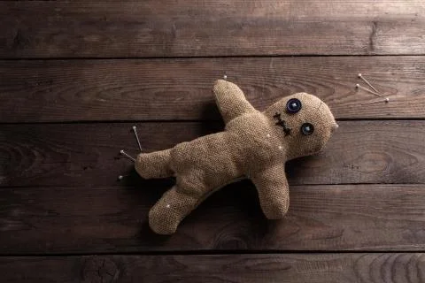 Voodoo doll on a wooden background with dramatic lighting. The concept of wit Stock Photos