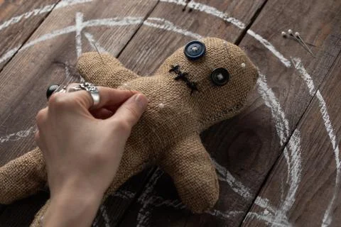 Voodoo doll on a wooden background with dramatic lighting. The concept of wit Stock Photos