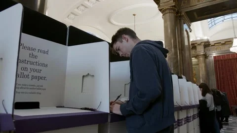 A voter completes a ballot paper at a voting booth Stock-Footage 345299117