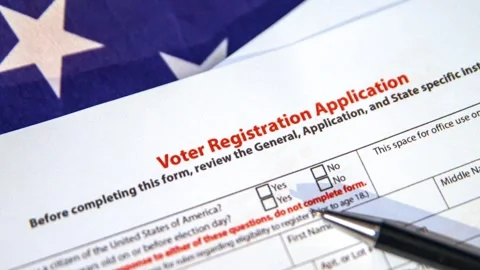Voter registration application form with USA flag in the backdrop Stock Footage 284844366