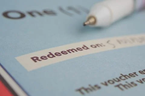 A voucher shows the redeemed date with a pen resting beside it Stock-Fotos