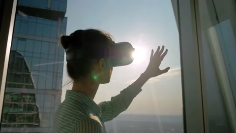 VR concept - young woman using virtual reality headset against skyscraper window Stock Footage 148784895