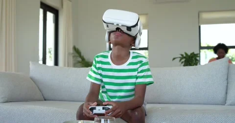 VR game starting, boy gripping controller and navigating VR world on sofa for Stock Footage 344325937