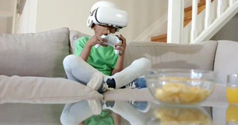 VR game starting, child is adjusting controller while leaning on couch to play, Stock Footage 336247558